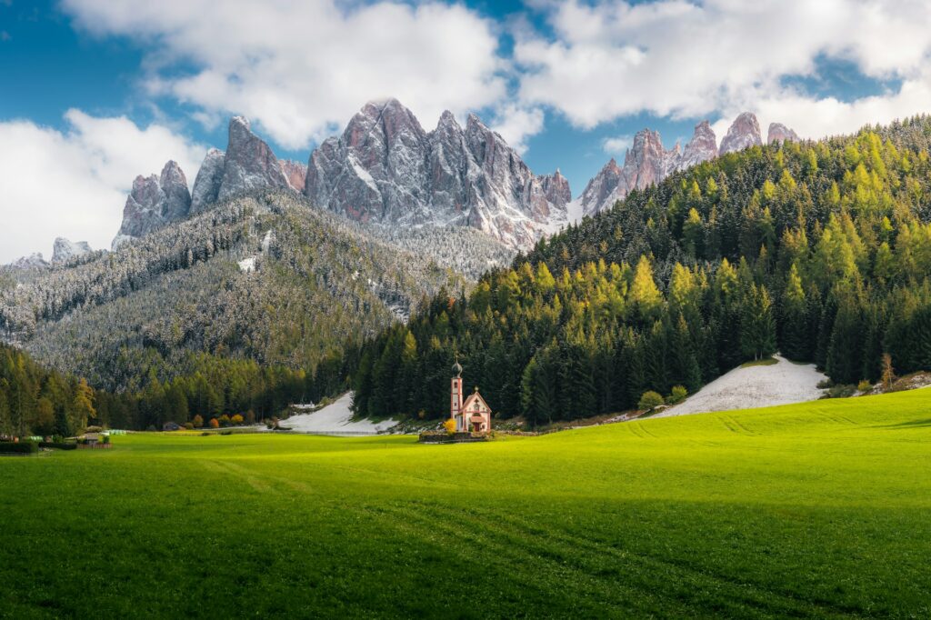 a church in a field in front of the Dolomites in Italy