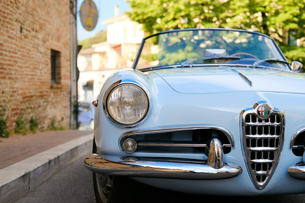 An Alfa Romeo car sits on a street in Italy